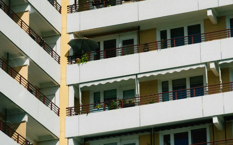 Fachada de edificio de apartamentos con balcones y toldos en un día soleado.